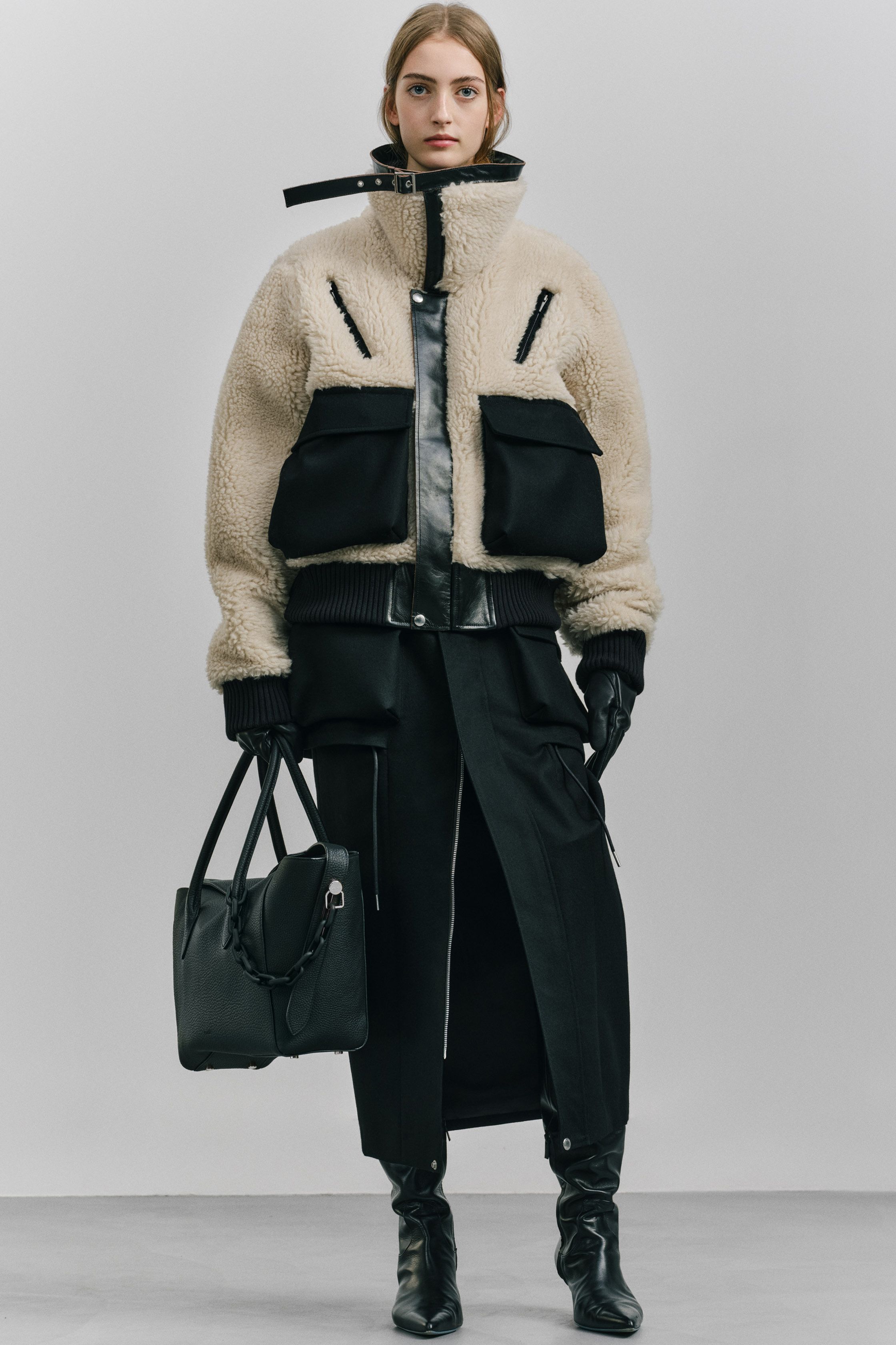 Sacai 本季继续以混合结构著称：羽绒服与西装外套、羊羔毛夹克与功能口袋结构交织在一起，打造层次丰富的机能时装。深色调与厚重面料让整体视觉更稳重，同时保持品牌标志性的结构拼接-顽石频道趋势研究